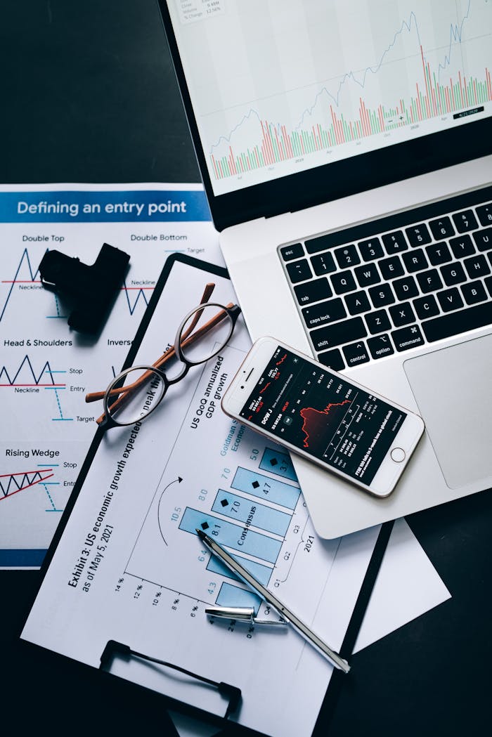 Top view of a workspace featuring financial graphs, a laptop, and a smartphone.